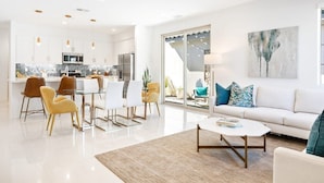 Una sala de estar moderna con un sofá blanco, una mesa de centro y un comedor con sillas y una mesa.