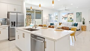 Una cocina moderna con armarios blancos, electrodomésticos de acero inoxidable y una isla central con asientos.