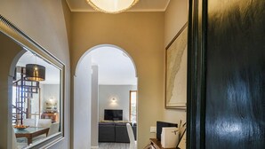 A hallway with a large mirror, a dark door, and a view into a living room with a sofa and TV. - Seaview Apartment With Garden by Wonderful Italy (Recco)