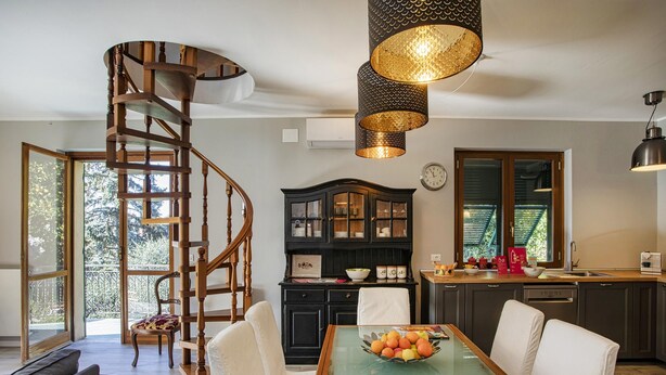 A modern kitchen with a spiral staircase, a dining table with a fruit bowl, and a large window. - Seaview Apartment With Garden by Wonderful Italy (Recco)