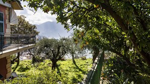 A balcony with a view of a lush garden and a distant mountain range. - Seaview Apartment With Garden by Wonderful Italy (Recco)