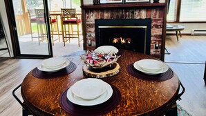 A dining table with plates and a centerpiece, a fireplace, and a view of the outdoors. - NEW Papa's Place on 1st hole Linville Land Harbor Pet Friendly  (Newland)
