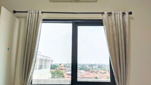 A room with a large window, curtains, and an air conditioning unit. - Yayah Guest House Syariah by Cocotel (Dramaga)