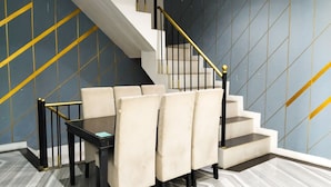 A staircase with a modern design, a seating area with chairs and a table, and a patterned floor. - Yayah Guest House Syariah by Cocotel (Dramaga)
