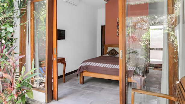 Un dormitorio con cama, mesita de noche y un ventanal con vistas a zonas verdes.