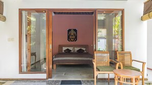 A bedroom with a bed, a chair, and a decorative wall piece. - Belvilla Nirvana Near Monkey ForestNearCampuhan Ridge Walk (Ubud)