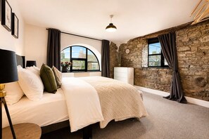 Ein Schlafzimmer mit einem Bett, einem Schminktisch, einer Lampe und einer Steinsäule.