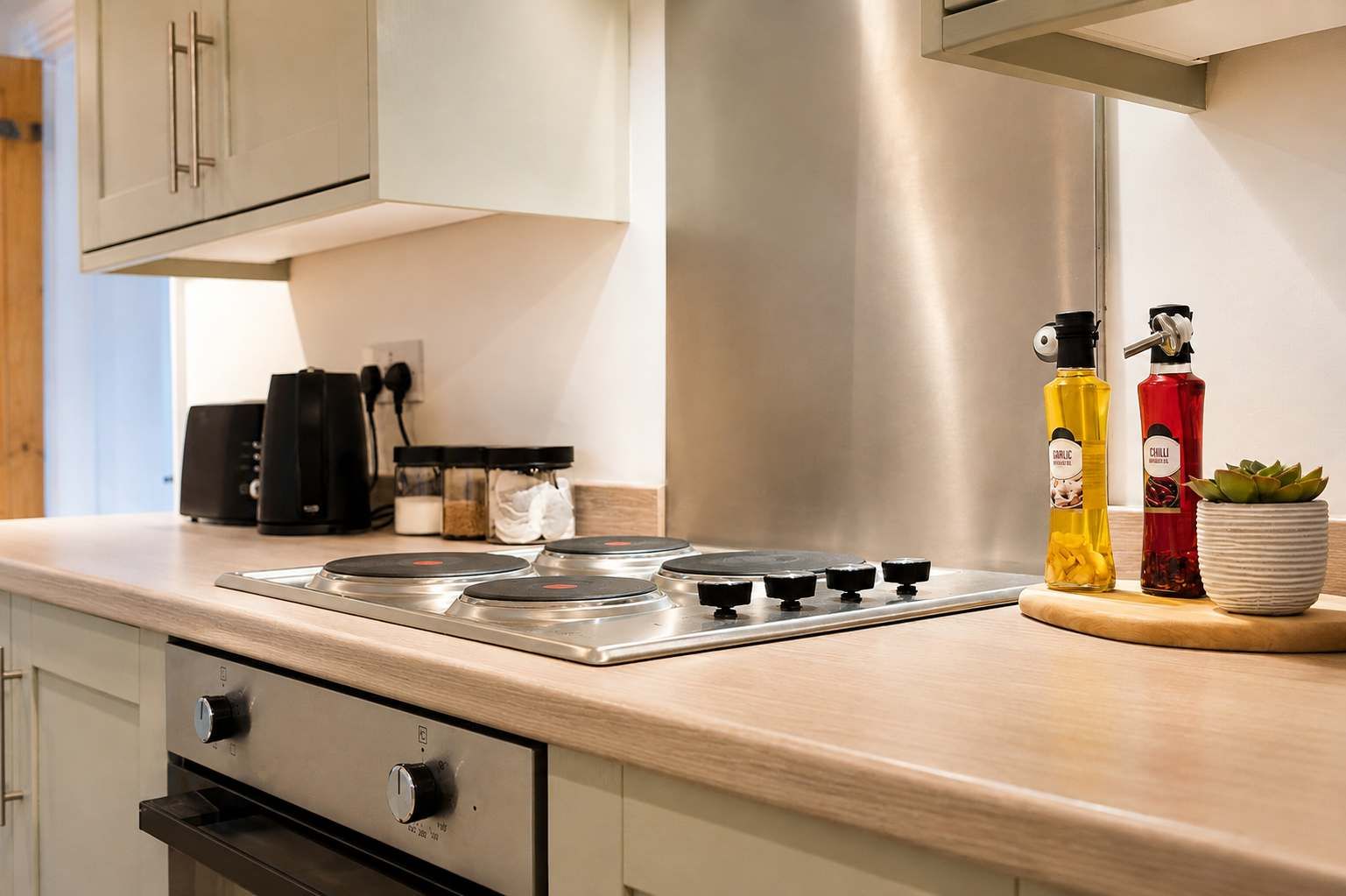 Une cuisine moderne équipée d’une cuisinière en acier inoxydable, d’une machine à café et d’une plante en pot.