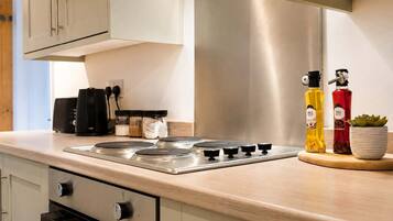 A modern kitchen with a stainless steel range, a coffee machine, and a potted plant.