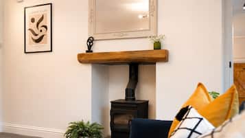 A living room with a fireplace, a framed artwork, and a mirror on the wall.