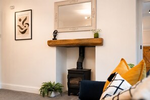 A living room with a fireplace, a framed artwork, and a mirror on the wall. - Cozy 3BR Family Home in Bowes | Sleeps 7 | Wi-Fi (Bowes)