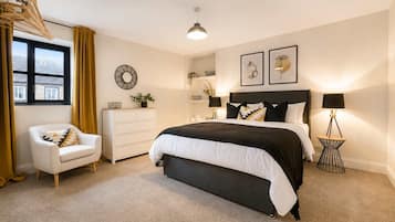 A bedroom with a bed, a chair, a dresser, a lamp, and a wall clock.