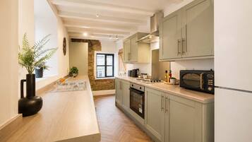 Une cuisine moderne avec des meubles en bois clair, un îlot central et un mur d’accent en pierre.