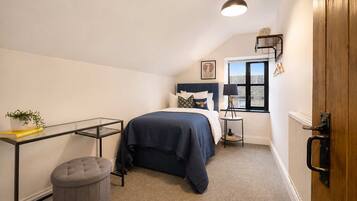 A bedroom with a bed, a bedside table, a lamp, a radiator, a window, and a door.