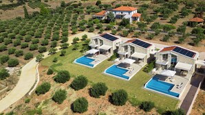 Zona residencial con varias casas, cada una con piscina y paneles solares.