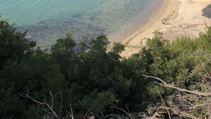 Una playa con aguas turquesas cristalinas, orilla de arena y exuberante follaje verde.