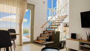 Una sala de estar moderna con una escalera, un comedor y una cocina.