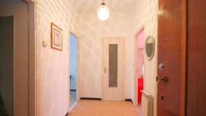 A narrow hallway with a wooden door on the right, a white door in the center, and a framed picture on the left wall. - Doria 6  (Andora)