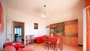 A dining area with a wooden table and chairs, a red sofa, and a cabinet with glass doors. - Doria 6  (Andora)