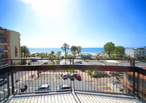 A balcony with a view of a parking lot, a building with a statue, and a clear blue sky. - Doria 6 (Andora)