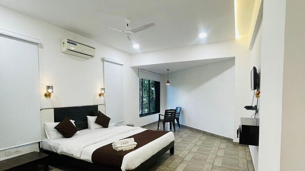 A modern hotel room with a large bed, a desk, and a chair. - Raj Resort (Palghar)