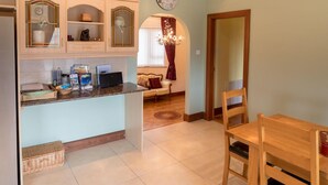 A kitchen with a built-in island, wooden cabinets, and a dining area with a wooden table and chairs. - Spacious House in Beautiful Malin Head (Malin)