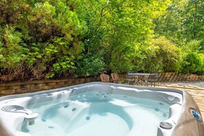 Un jacuzzi rodeado de exuberante vegetación y un muro de ladrillo.