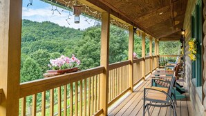 A wooden deck with a railing, potted flowers, and outdoor seating. - Escape to the Dulce Mountain Cabin in Bryson City, NC (Bryson City)