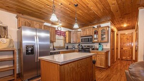 A kitchen with wooden cabinets, a stainless steel refrigerator, a microwave, and a coffee maker. - Escape to the Dulce Mountain Cabin in Bryson City, NC (Bryson City)
