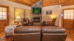 A cozy living room with a stone fireplace, leather sofas, and wooden flooring. - Escape to the Dulce Mountain Cabin in Bryson City, NC (Bryson City)