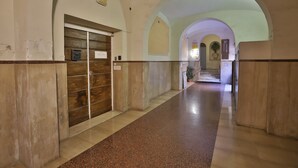 Un corridoio con soffitti a volta e una porta in legno con un cartello.