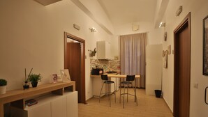 Una cucina compatta con un piano di lavoro in legno, due sgabelli da bar e un forno a incasso.