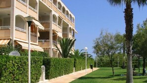Un hotel de varios pisos con balcones, un césped bien cuidado y palmeras.