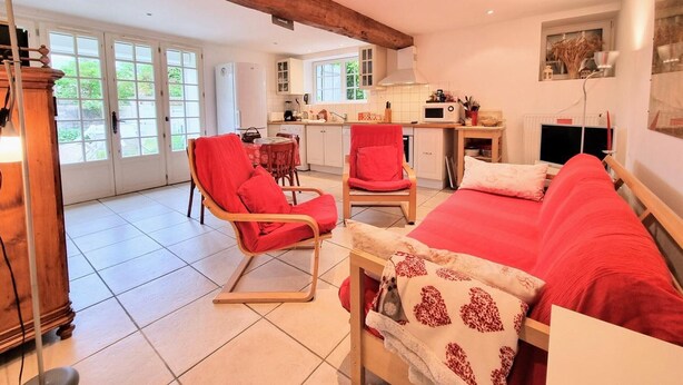 Une pièce confortable avec un lit, un canapé rouge et un coin repas comprenant une table et des chaises.