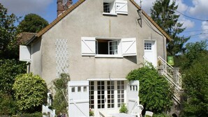 Une maison à deux étages, avec une façade blanche, une cheminée et un petit balcon.