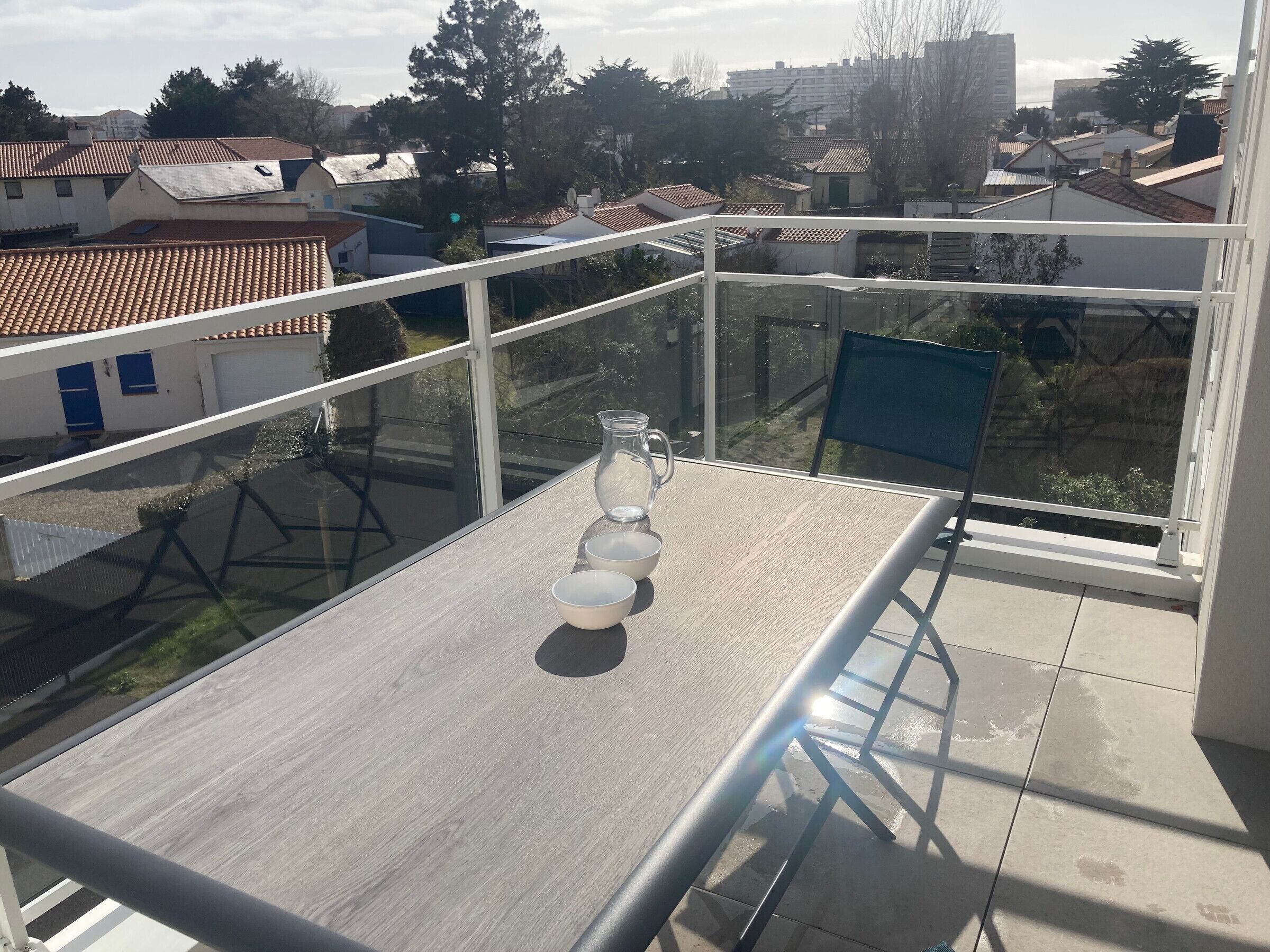 A balcony with a table, chairs, and a glass pitcher.