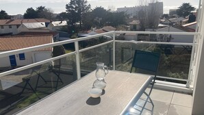 Un balcón con mesa, sillas y una jarra de vidrio.