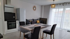 Una cocina moderna con zona de comedor, que incluye una mesa grande, sillas y un horno empotrado.