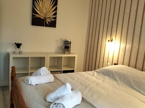 A neatly made bed with white linens, a bedside table with a lamp, and a wall-mounted artwork. - Charming Home in Verdant Vôge - Hike, Bike, and Relax Nearby (Montmotier)