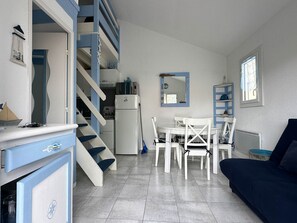 A compact living space with a kitchen, dining area, and a staircase leading to an upper level.