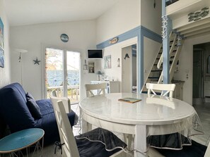 Relax in this inviting living space with a round dining table, comfortable sofa, and large window offering a view of the outdoors.