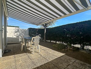 Relax in a shaded patio area with a gravel floor, surrounded by a low wall and a beautifully manicured hedge.