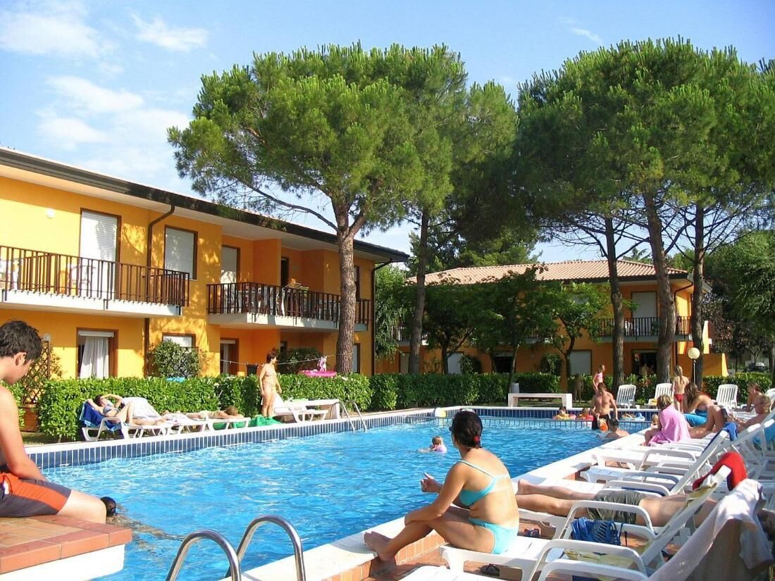 A pool area with lounge chairs and a building with balconies.