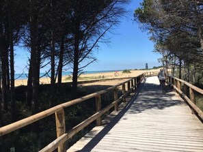 A wooden boardwalk leading to a beach with a clear view of the ocean. - Comfy flat in Bibione (Bibione)