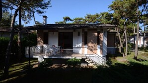 A two-story house with a balcony, surrounded by trees. - Beautiful terraced apartment in a great location (Lignano Sabbiadoro)