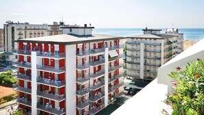 A multi-story hotel with balconies, a beach view, and a parking area. - Functional house close to the beach (Bibione)