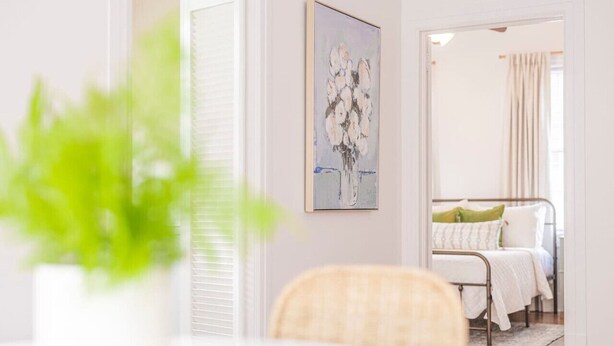Un dormitorio con cama, mesita de noche y ventana con cortinas.