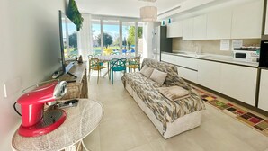 A modern living room with a sofa, a dining table, and a kitchen area. - Golden Hour Retreat Lagoon View Villa With Pool (Rosolina)