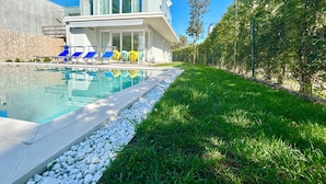 A modern house with a swimming pool, a covered patio, and a well-maintained lawn. - Golden Hour Retreat Lagoon View Villa With Pool (Rosolina)
