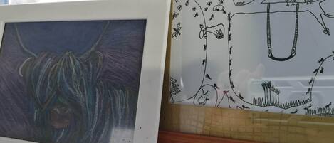 Dos obras de arte enmarcadas, una con un toro y la otra con un paisaje que incluye árboles y un puente.